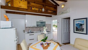A compact kitchen with white cabinets, a microwave, and a sink. There's a dining table with a white tablecloth and a basket of items. A sofa and a bed are in the living area.