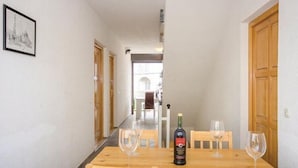 A dining area with a wooden table, two chairs, and a bottle of wine.