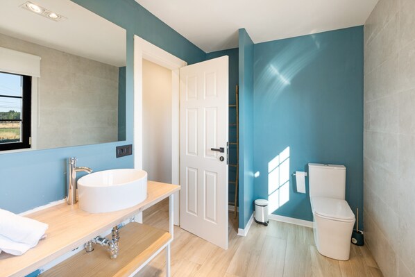 Un bany modern amb un lavabo blanc, un mirall i un vàter.