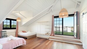 A bedroom with a sloped ceiling, a bed, a window with a view, and a hanging light fixture. - Country House 'Camino Blanco' with Private Pool, Shared Terrace and Air Conditioning (IBEAS DE JUARROS)