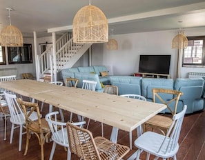 A spacious living area with a long wooden table, white chairs, a blue sofa, and wicker pendant lights. - Country House 'Camino Blanco' with Private Pool, Shared Terrace and Air Conditioning (IBEAS DE JUARROS)