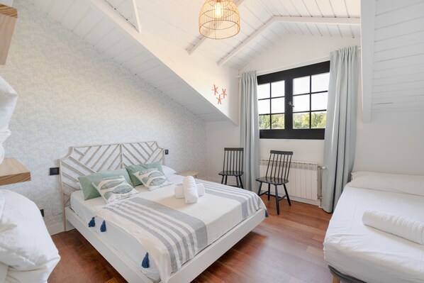 Une chambre à coucher avec un lit, deux chaises, une fenêtre avec des rideaux et un luminaire au plafond.