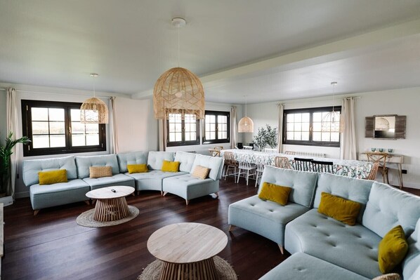 A spacious living area with a sectional sofa, round coffee table, and dining table with chairs. - Country House 'Camino Blanco' with Private Pool, Shared Terrace and Air Conditioning (IBEAS DE JUARROS)