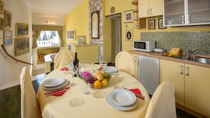 Un coin repas avec une table dressée pour quatre personnes, une cuisine avec des meubles jaunes, un four à micro-ondes et un évier.