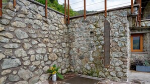 A stone wall with a metal door, a small window, and a potted plant. - Studio Apartment 'Maso Plocech App Vacanze' with Lake View, Private Garden and Wi-Fi (Pergine Valsugana)