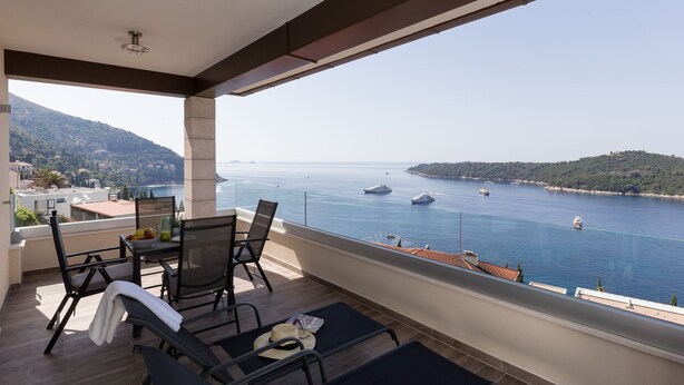 Ein Balkon mit Meerblick, einem Tisch mit Stühlen und einem Hut auf dem Boden.