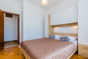 Une chambre avec un lit en bois, des armoires blanches et un plancher en bois.