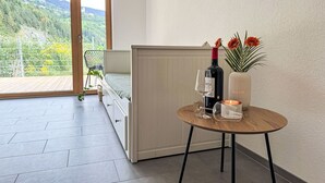 Ein modernes Schlafzimmer mit Balkon, einem Bett, einem runden Tisch mit einer Weinflasche, einer Kerze und einer Vase mit Blumen.