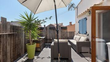 A patio with outdoor furniture, a potted plant, and a wooden fence.