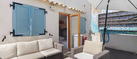 A patio area with a sofa, chairs, and a large umbrella.