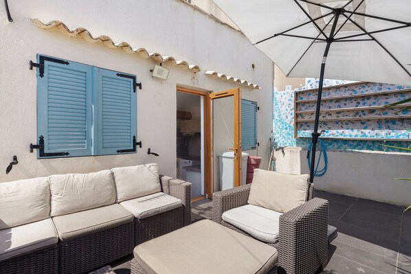 Un espace extérieur aménagé avec un canapé, des chaises et un grand parasol.