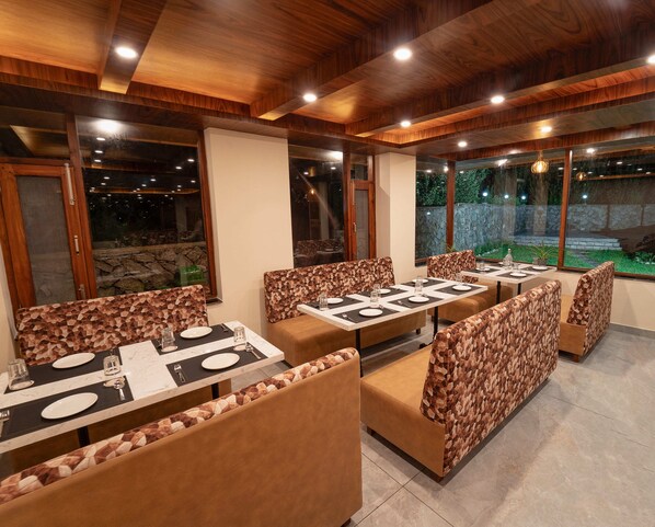 A restaurant with wooden ceiling, large windows, and booth seating. - NAZAARA - A Luxe Retreat (Manali)
