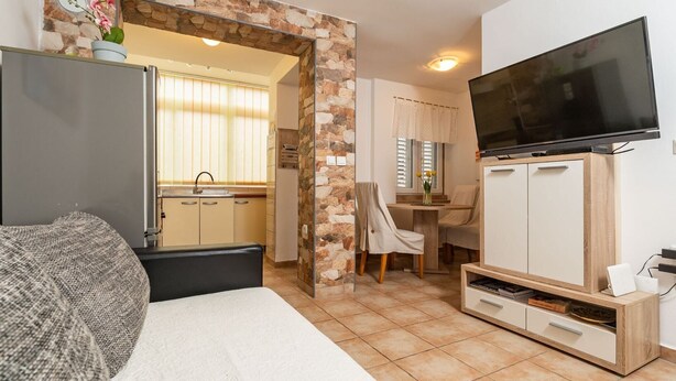 Une chambre d’hôtel avec un lit, une télévision, une kitchenette et un mur en pierre.