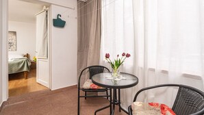 Un balcon avec une table et des chaises, un sac suspendu et un lit en arrière-plan.
