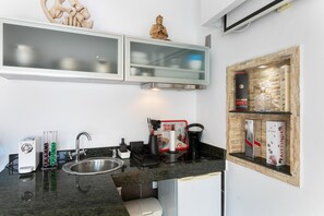 Una cocina con encimera de granito, pileta de acero inoxidable, cafetera y un mueble con un adorno encima.