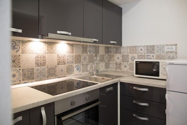 A modern kitchen with a built-in microwave, a sink, and a stove.