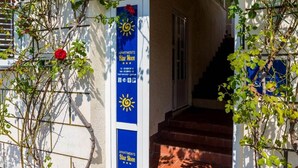 A building entrance with a blue sign for Blue Moon Apartments, a staircase, and climbing plants.