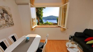 Una habitación con una mesa de comedor, sillas, un sofá y vistas a un lago a través de una ventana.