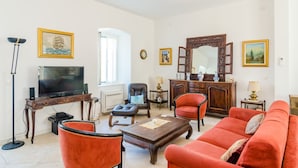 A living room with a television, red sofa, and a wooden cabinet.