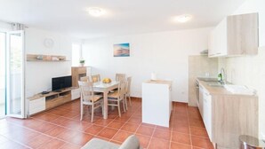 A compact kitchen with a dining area, a TV, and a small island.