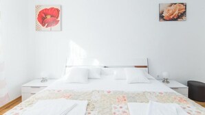 A neatly made bed with white linens, a floral-patterned bedspread, and two bedside tables with lamps.