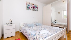 Une chambre à coucher avec un lit, une table de chevet, un miroir et un tableau accroché au mur.