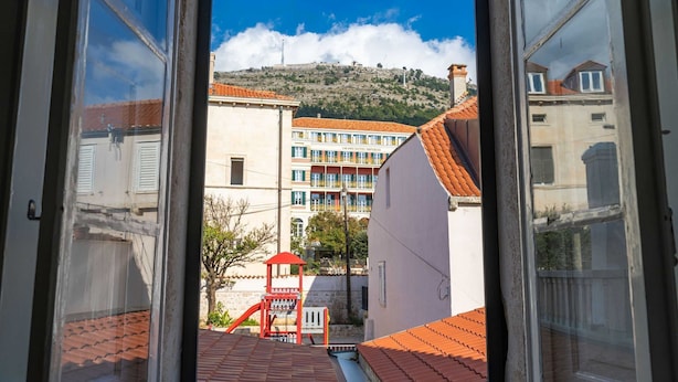 A view from a window overlooking a building with a red roof and a playground.