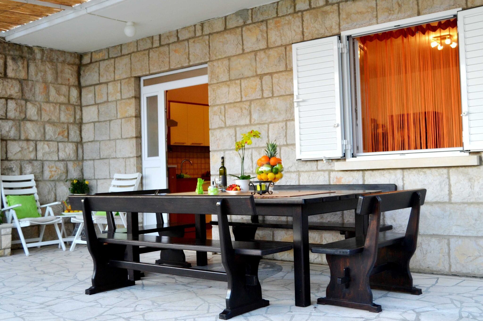 An outdoor patio with a stone wall, a wooden table, and benches.