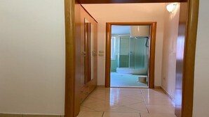 Un couloir menant à une salle de bain équipée d’une douche et de toilettes.