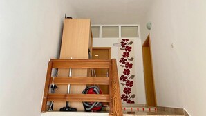 Een trap met een houten leuning, een rode stofzuiger en een deur met een bloemendecoratie.