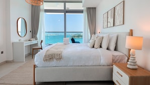 A modern hotel room with a large bed, a desk, and a view of the sea. - HiGuests - Azure Residences (Dubai)