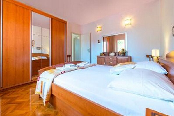Habitación de hotel con una cama grande, un armario de madera y un espejo.