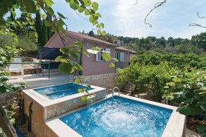Una casa de dos pisos con piscina y un patio cubierto.