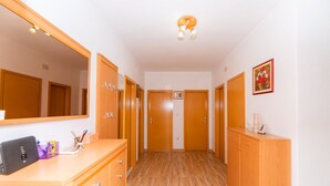 A hallway with wooden doors, a mirror, and a small desk with a computer and stationery.