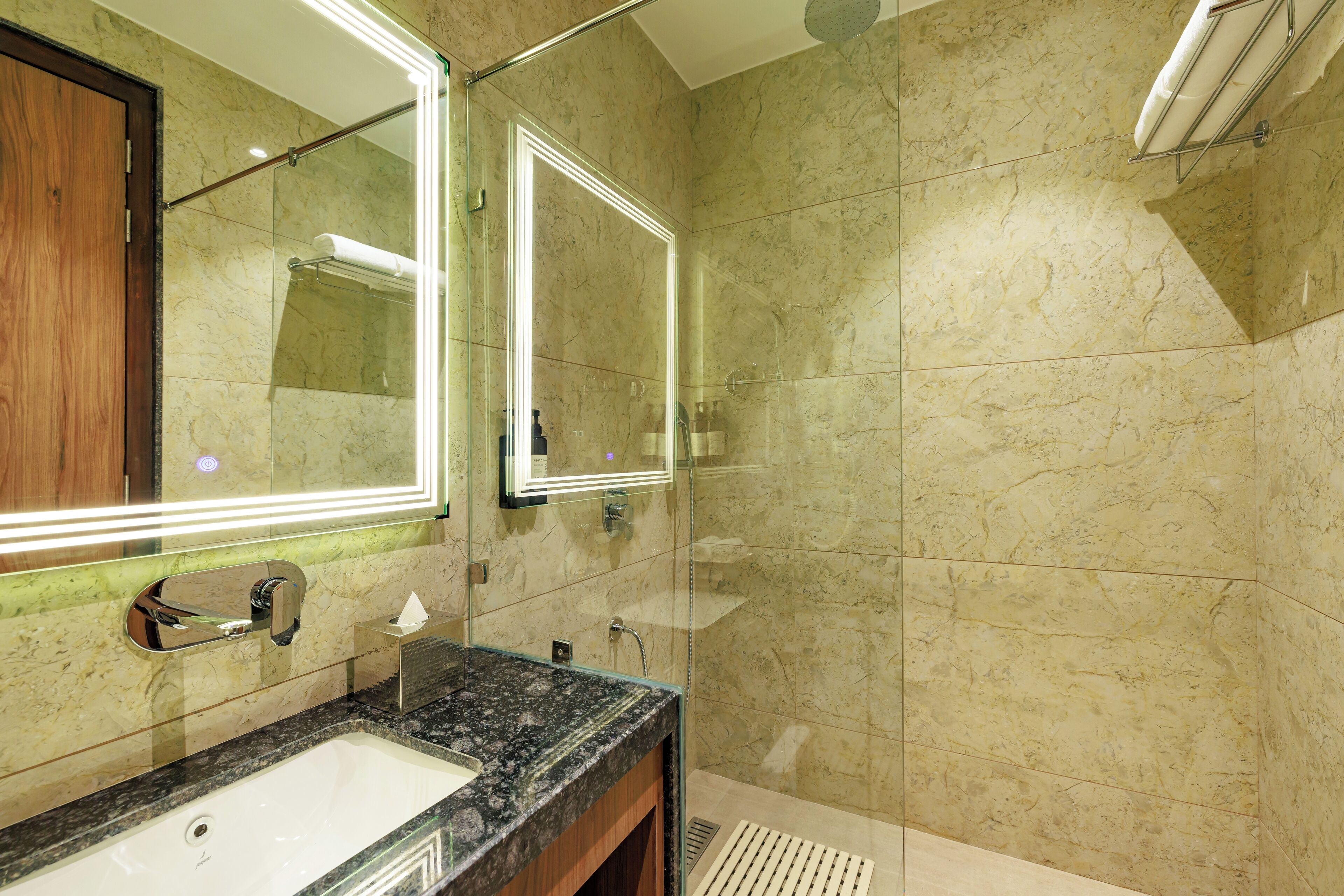 A modern bathroom with a marble sink, a large mirror, and a glass-enclosed shower.