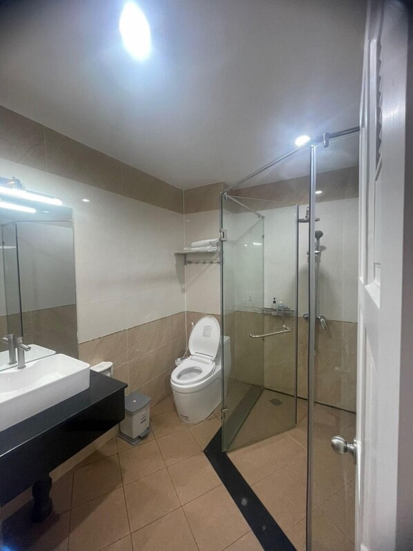 A modern bathroom with a glass-enclosed shower, a white toilet, and a sink with a mirror above it. - Good For You Hotel (Ho Chi Minh City)