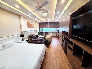 A hotel room with a bed, massage chair, TV, and a balcony with a view. - Good For You Hotel (Ho Chi Minh City)
