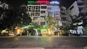 Un hotel con un cartel que dice "BINHAN HOTEL" y "GOOD FOR YOU" de noche.