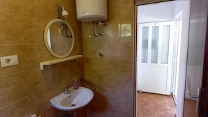 A bathroom with a white sink, mirror, and a toilet. There is a white door with frosted glass panels and a white radiator on the wall.