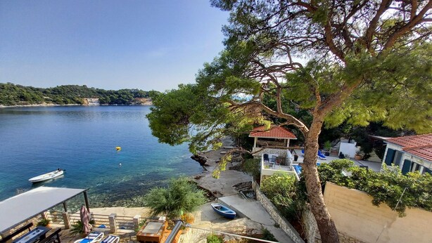 A coastal property with a swimming area, lounge chairs, and a view of the sea.