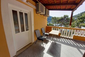 A balcony with a table and chairs, overlooking a scenic view of trees and hills. - Apartments Vinko Mljet- One-Bedroom Apartment with Terrace (A5) (Sobra)
