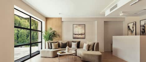 A modern living room with a large window, a sectional sofa, a coffee table, and a white reception desk.