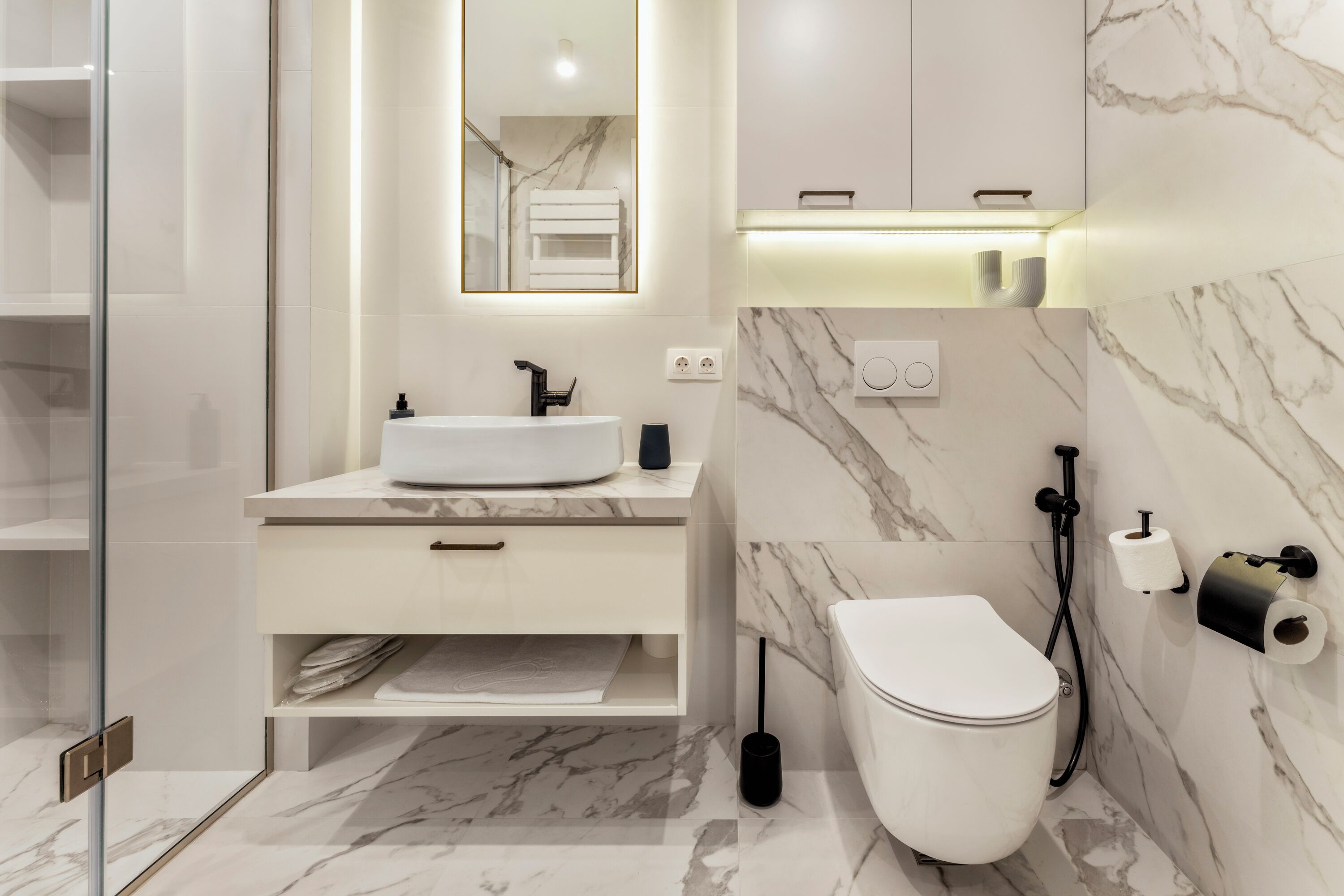 A modern bathroom with a white sink, a toilet, and a glass shower enclosure.