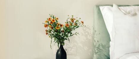 A neatly arranged bedside table with a vase of flowers, a book, and a coffee mug.