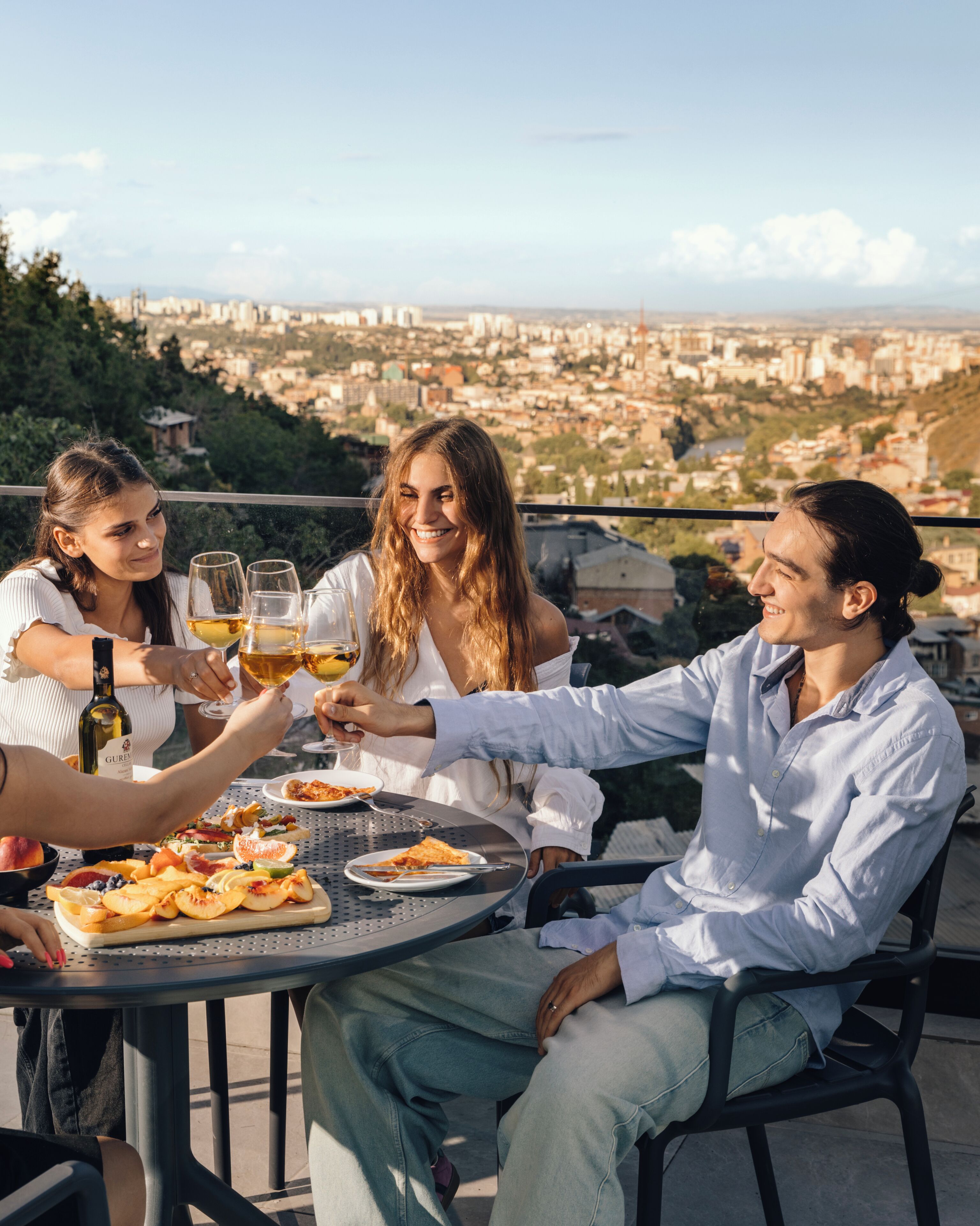 Un groupe de personnes porte un toast autour d’une table, avec une vue sur la ville en arrière-plan.