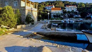 A stone building with a red roof near a body of water with boats. - Guest House Kiko - Budget Twin Room - No.1 (Pomena)