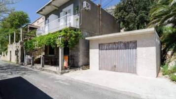 Un bâtiment à deux étages doté d’un balcon, d’un garage et d’un mur en pierre.