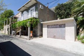 A two-story building with a balcony, a garage, and a stone wall.