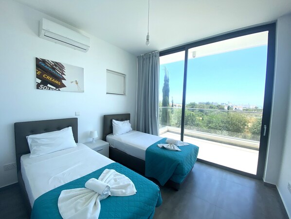 Une chambre d’hôtel avec deux lits, une grande fenêtre donnant sur la ville et un climatiseur fixé au mur.