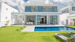 Ένα σύγχρονο διώροφο σπίτι με πισίνα, εξωτερικό χώρο καθιστικού και σπειροειδή σκάλα.